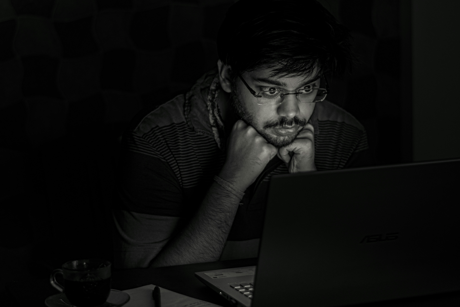 Young Indian man looking at his laptop late at night